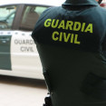 Archivo - Un agente de la Guardia Civil, de espaldas, junto a un vehículo oficial.