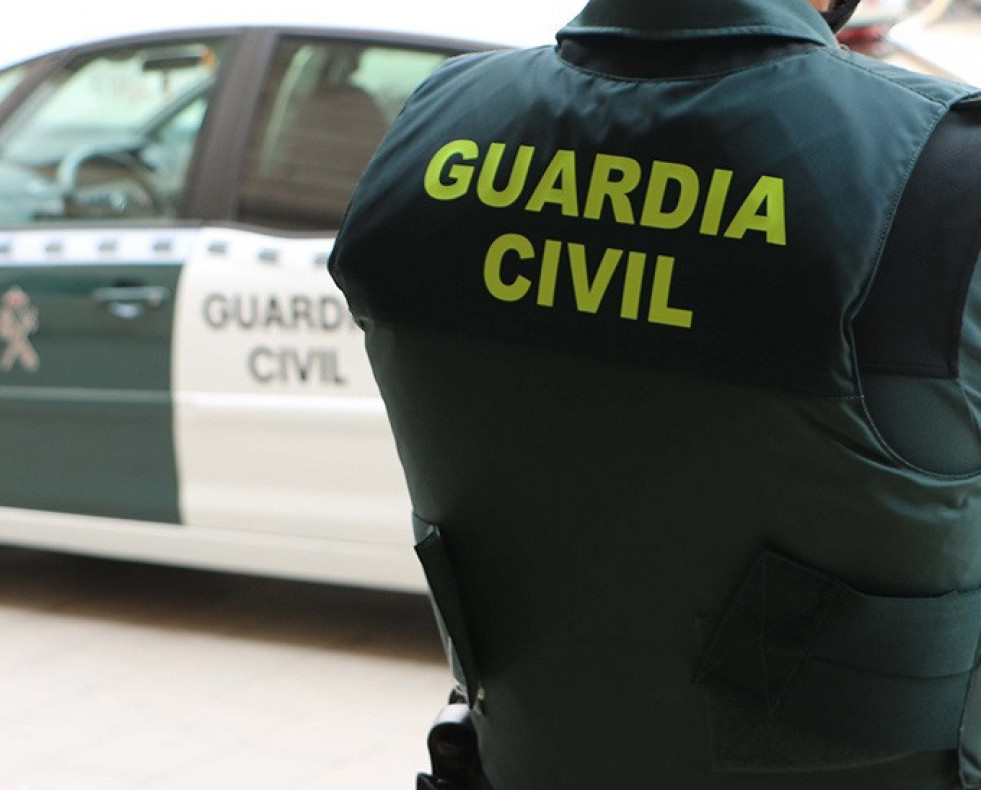 Archivo - Un agente de la Guardia Civil, de espaldas, junto a un vehículo oficial.