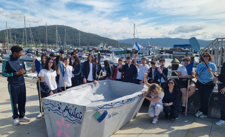 El alumnado del colegio Santa Apolonia hace navegar un barco de cartón en la ría de Muros