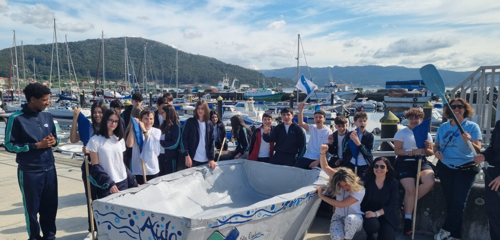 El alumnado del colegio Santa Apolonia hace navegar un barco de cartón en la ría de Muros