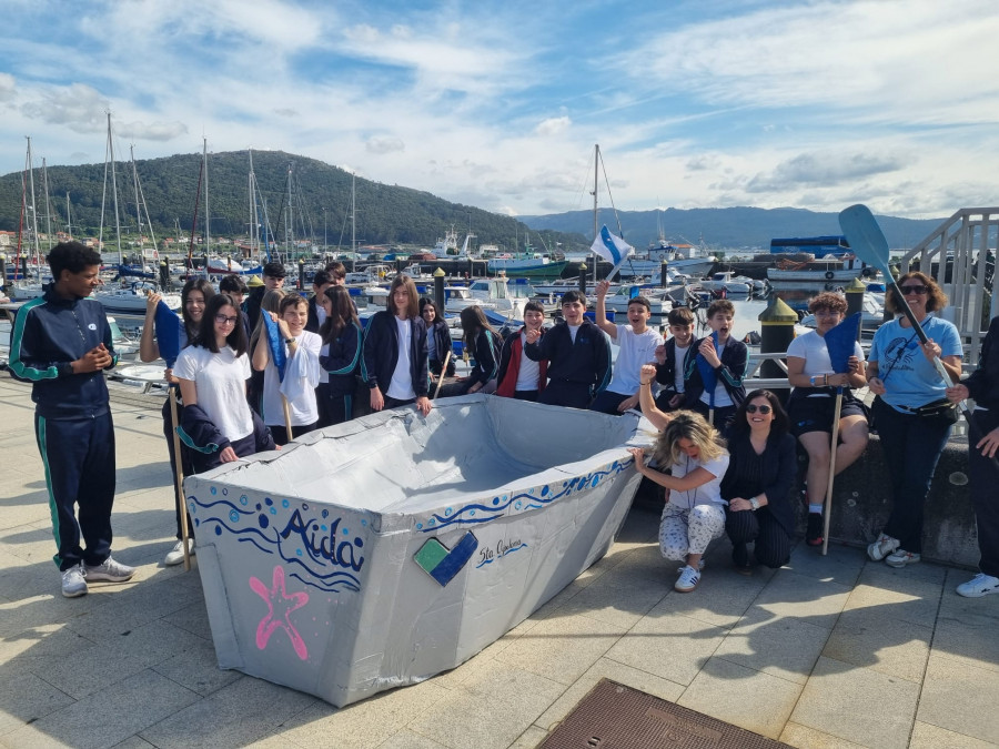 El alumnado del colegio Santa Apolonia hace navegar un barco de cartón en la ría de Muros