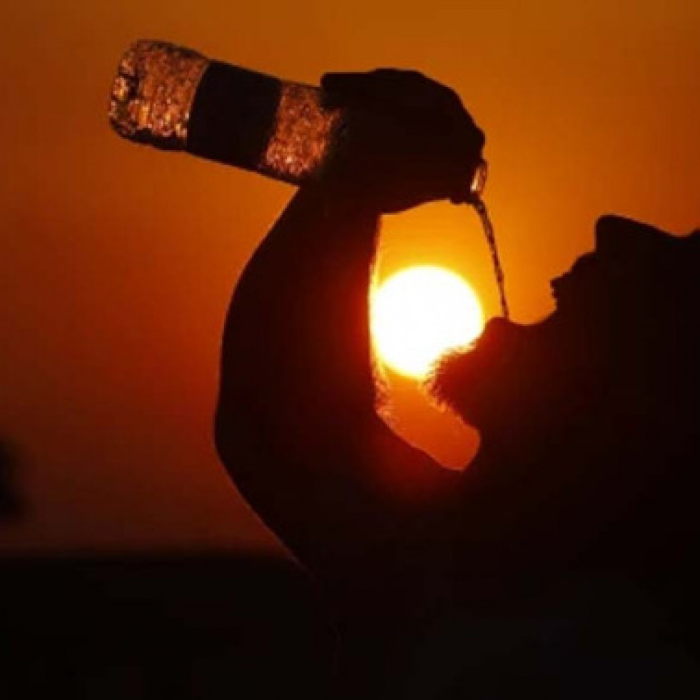 Personabebiendounabotelladeaguaporoladecalor